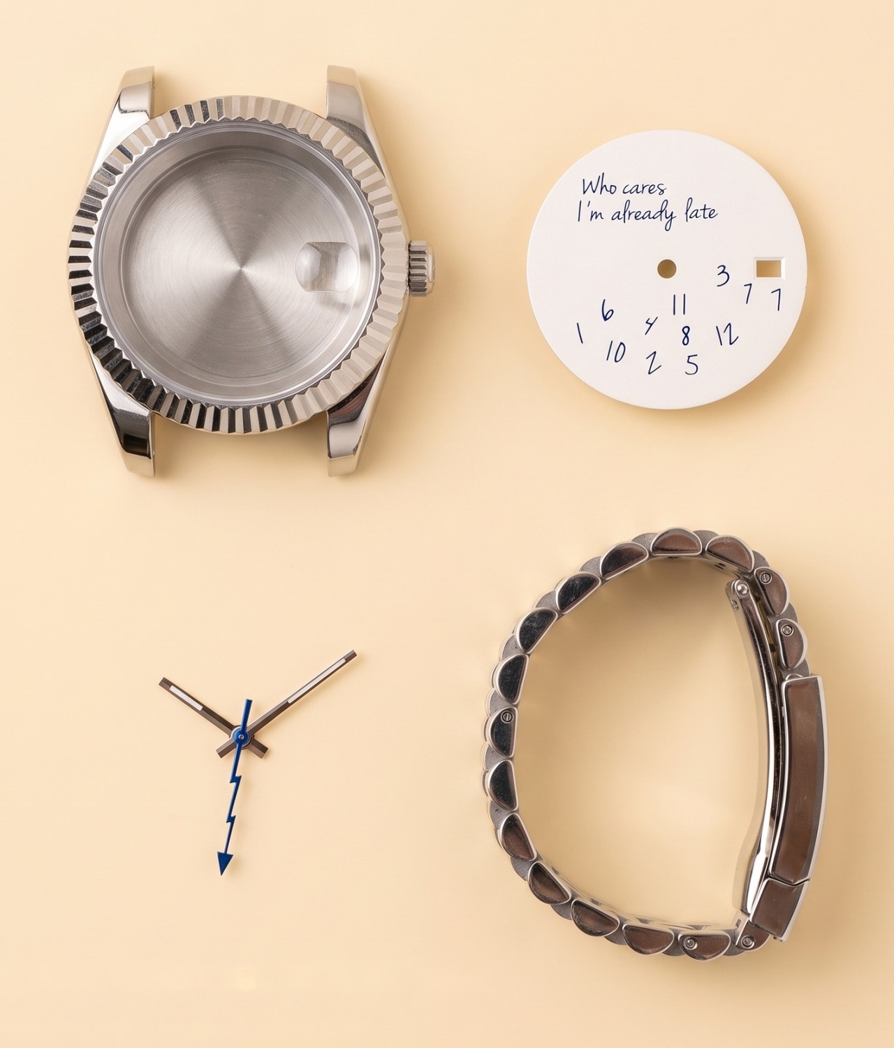 A fluted steel case, a handwriting-style dial, a set of hands and a jubilee bracelet laid out on a cream surface, the four things you choose in the Eximius builder